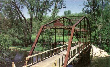 photo of a wrought iron bridge with wooden deck