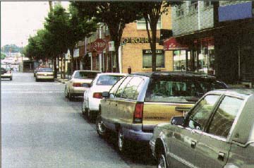photo of cars parked on a street and an intersection with a stop sign