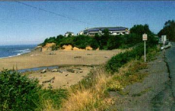 photo: beach with Pacific Ocean to the left and a building in the distance