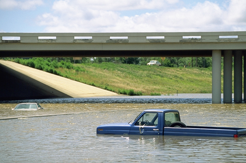 Photo.  Two cars nearly submerged on a flooded roadway.