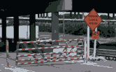 Manually operated gate located immediately below and front a bridge overpass.  The gate is in the closed position. 