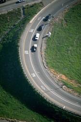 Photograph: An aerial photograph of a freeway entrance ramp with one metered general all purpose lane and one HOV lane. The photograph shows three vehicles queued at the ramp meter with another vehicle pulling away from the ramp meter.