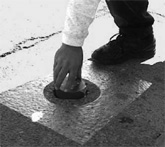 Photo of man touching vehicle detector embedded in parking lot surface