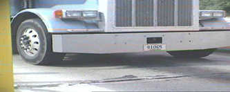 Four part image, showing images captures by automatic license plate reader cameras. Mid-Top:  wide angle view of semi tractor, with license plate numbers clearly visible.