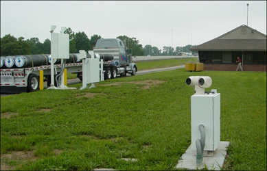 View of thermal imaging camera pedestal, with Integrated Safety and Security Enformcement System portal apparatus and weigh station scale house in the background (Laurel County, KY)
