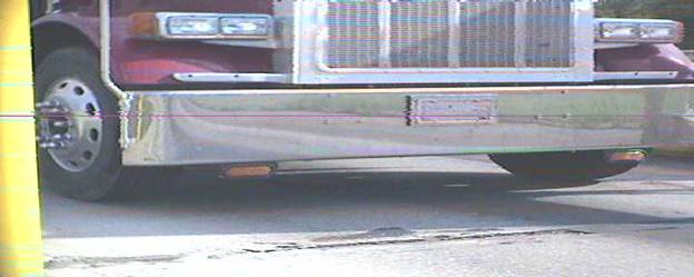 Figure 14. Photo montage. The first of four photographs showing image captures by automatic license plate reader cameras.  This photograph shows a wide angle view of the front bumper of a semi tractor, with no license plate number visible.