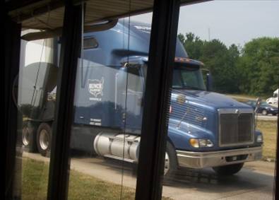 Figure 16. Photograph. View of a truck tractor as seen through large windows from inside the scale house, with the truck passing a few feet away from the observer’s location.